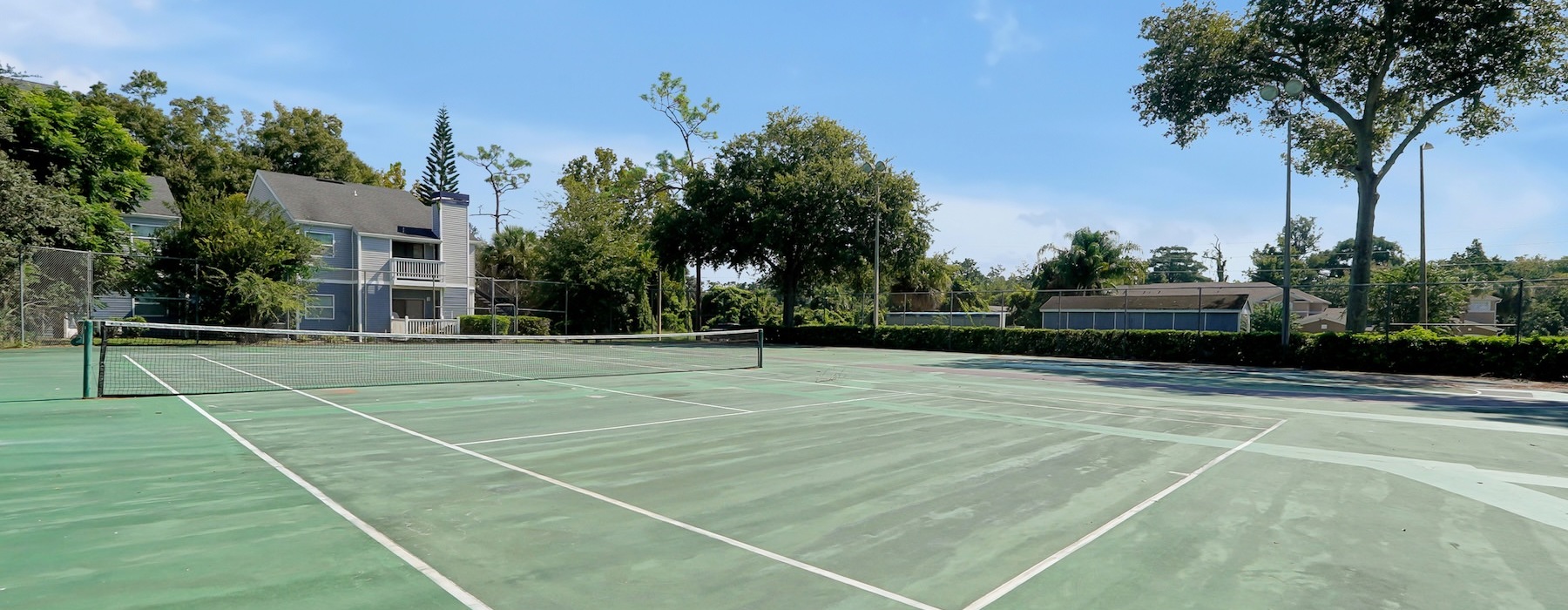 a tennis court with trees and houses in the background