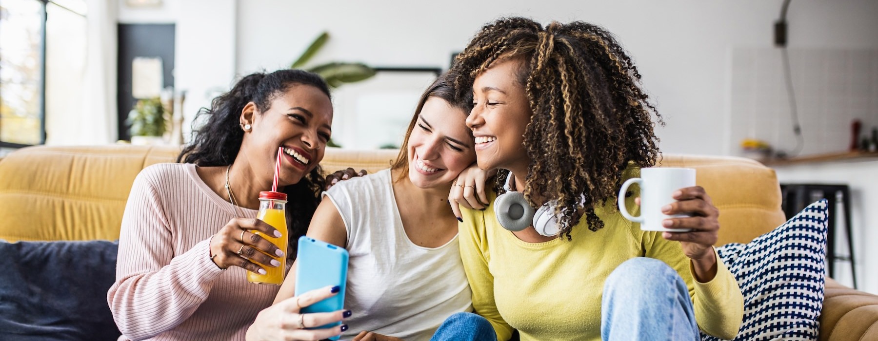 a group of women sitting on a couch looking at a phone
